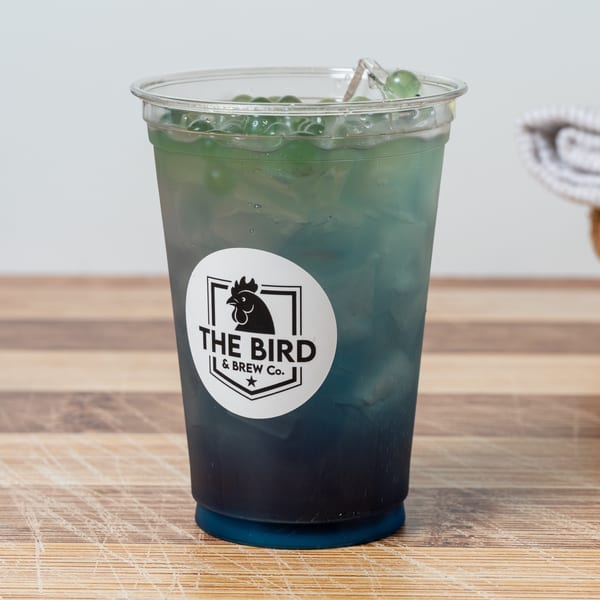 A blue and green iced drink with popping boba and a "The Bird & Brew Co." logo.